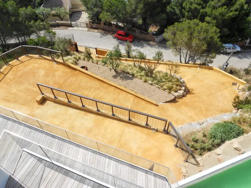 Vista aèria d’una terrassa enjardinada amb paviment de color sorra i barana metàl·lica
