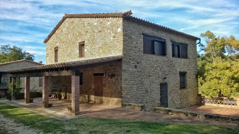 Masia de pedra amb porxo de fusta i coberta de teula