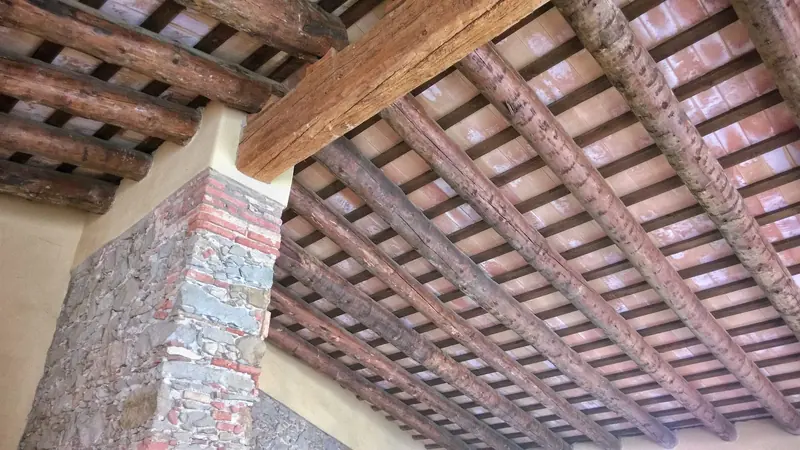 Sostre de bigues de fusta i revoltons de rajola amb un pilar de maó
